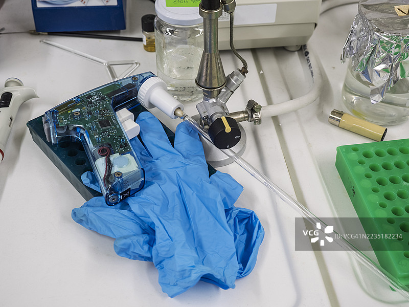 实验室中的工作台，上面有移液管和手套。图片素材