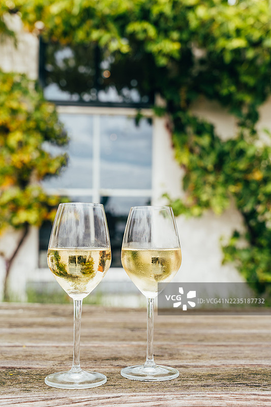 两杯冰镇的白葡萄酒，摆放在户外的乡村风格木桌上图片素材