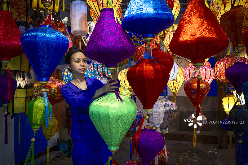 一名女子在商店里布置五彩灯笼图片素材