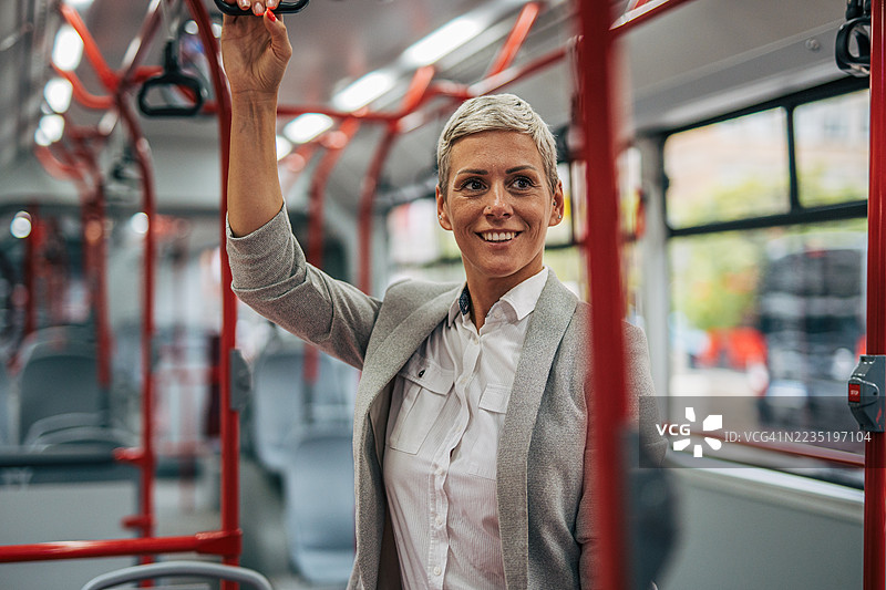 微笑的女商人在通勤时握着公交车的扶手图片素材