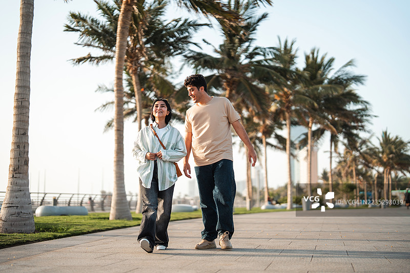年轻情侣在海滨长廊散步享受时光图片素材