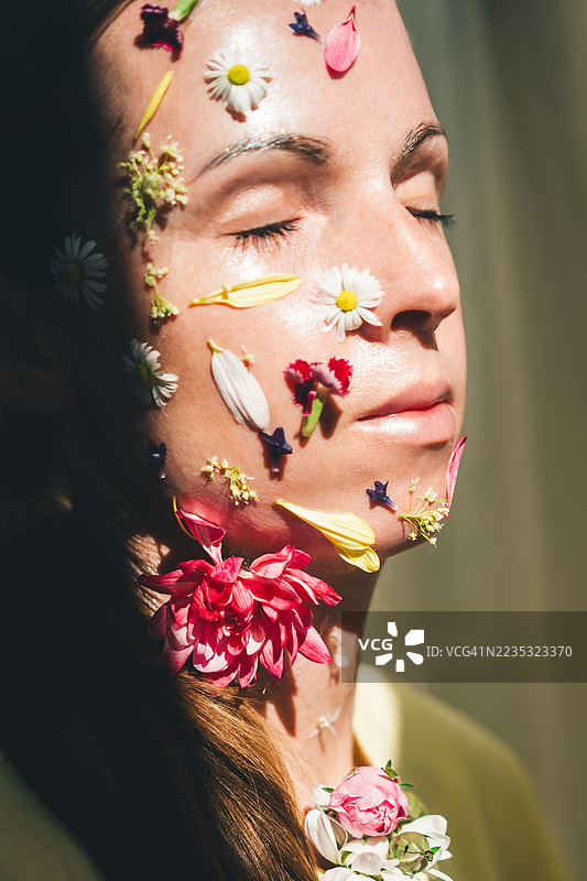 一位面部装饰着花朵的女性肖像，体现了一位中年女性逐渐消逝的美丽。图片素材