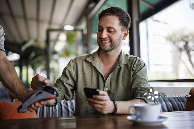 年轻男子在咖啡馆用信用卡付款图片素材