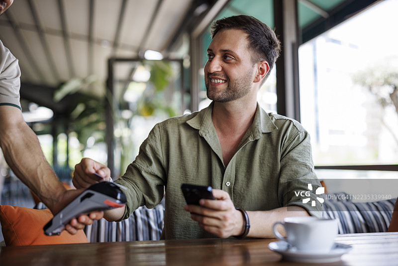 年轻男子在咖啡馆用信用卡付款图片素材