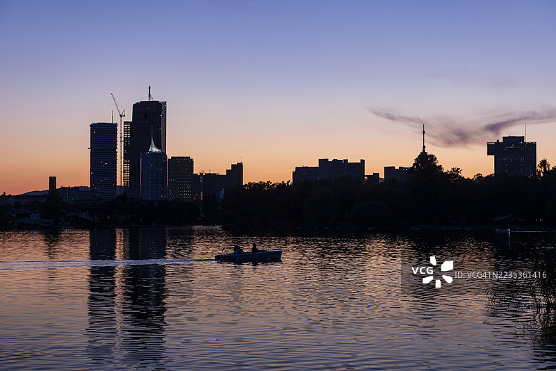 阿尔特多瑙河在蓝色黄昏的天空下闪烁，远处维也纳的丹瑙城市天际线微微勾勒。图片素材