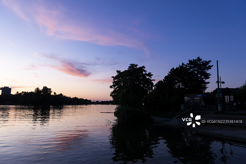 阿尔特多瑙河在蓝色黄昏的天空下闪烁，远处维也纳的丹瑙城市天际线微微勾勒。图片素材