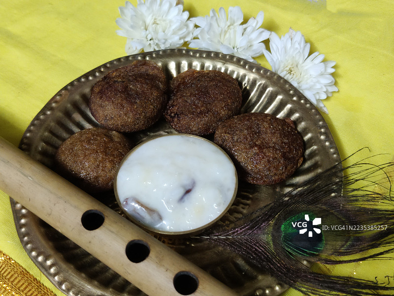 Unni appam/unniyappam/帕尔奶酪/米布丁/铜盘中的布丁/花朵/竹笛/孔雀羽毛在黄色丝绸布上/斯里克里希纳诞辰节/斯里克里希纳节/阿什塔米罗希尼节/节日/喀拉拉邦图片素材