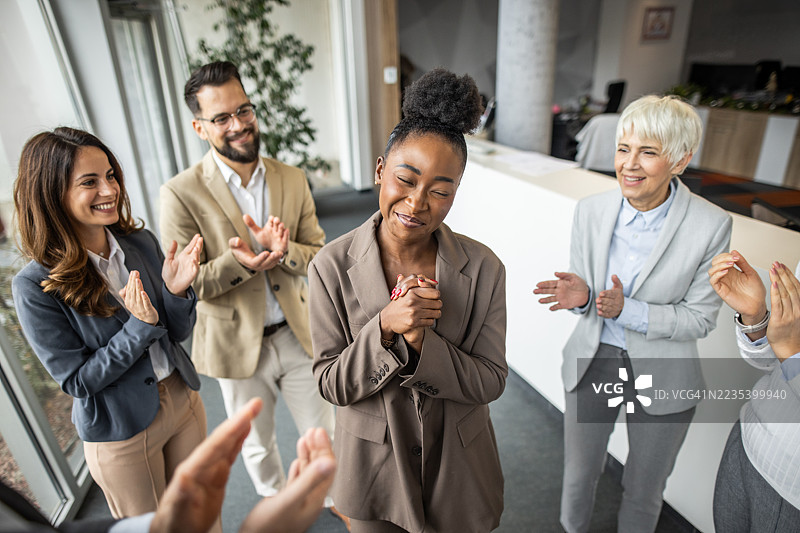 感激的女商人在办公室里接受同事们的掌声图片素材