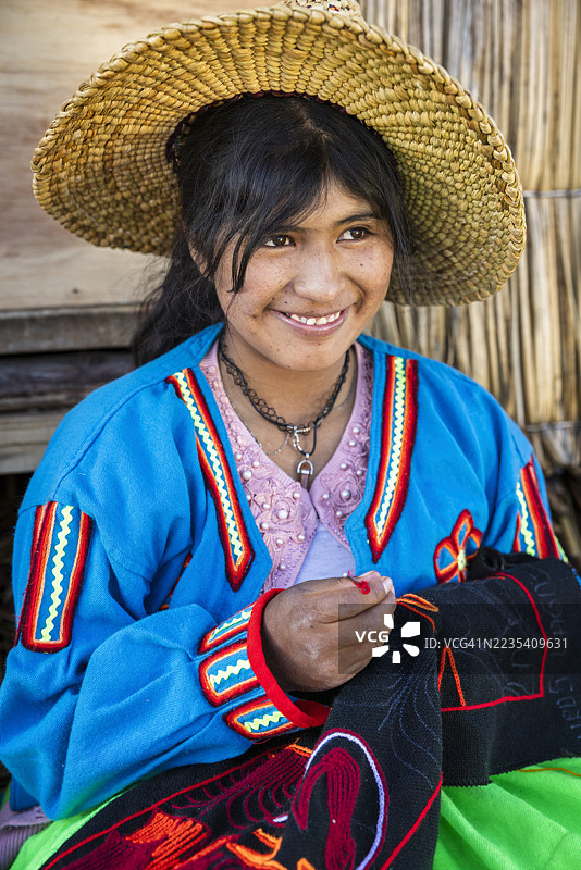 秘鲁年轻女性在的的喀喀湖乌罗斯浮岛上出售纪念品图片素材