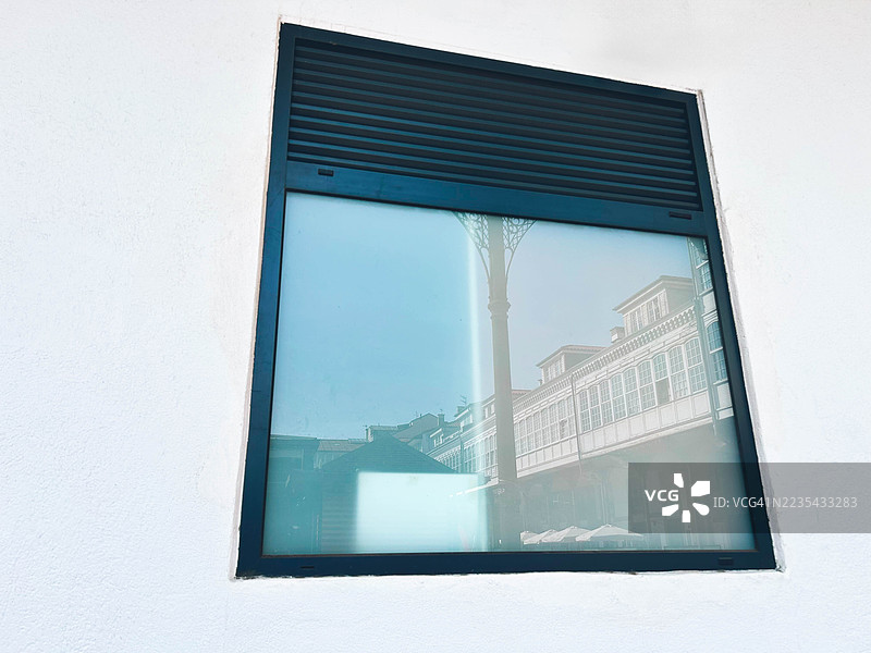 窗户中映射的建筑物。西班牙阿维莱斯，阿斯图里亚斯。图片素材