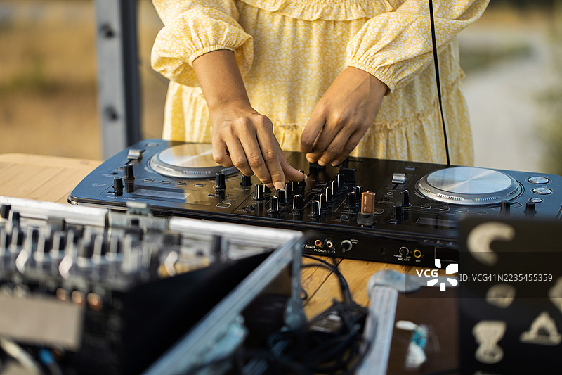在阳光明媚的白天，DJ在户外音乐活动中操作混音器图片素材