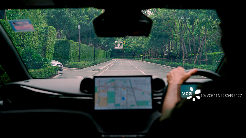 一名亚洲成年男子在农村地区开车时，正仔细查看GPS上的目的地。图片素材