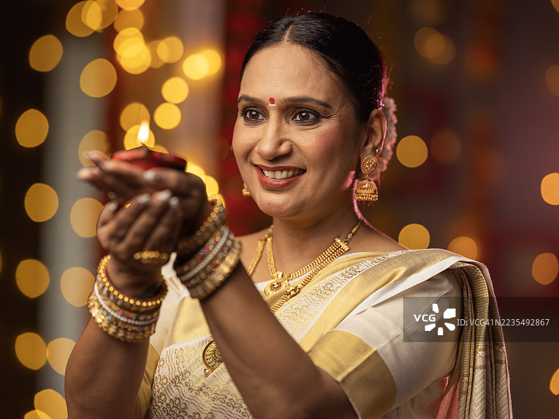 女人在家中庆祝排灯节时手持油灯图片素材