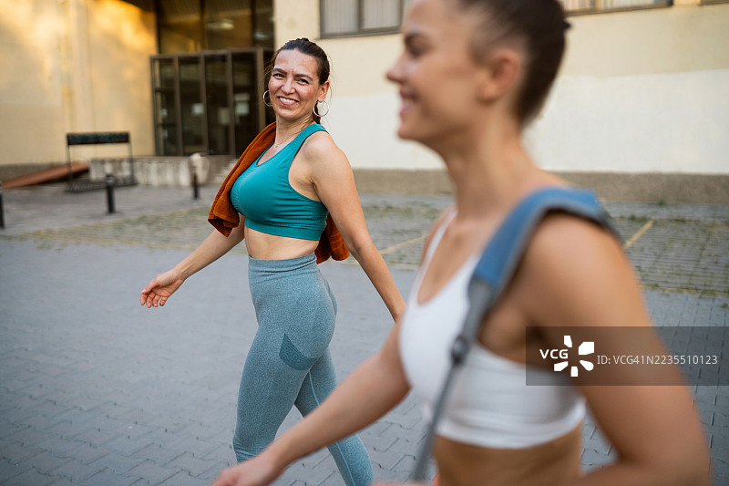 两位女运动员训练结束后，在回家的路上边走边聊，开怀大笑。图片素材