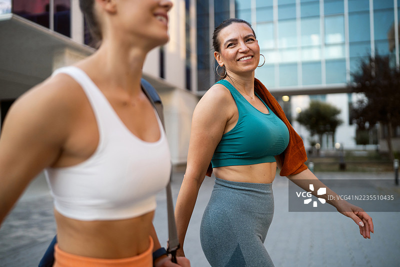 两位女士健身后边走边聊，面带笑容地走在回家的路上图片素材