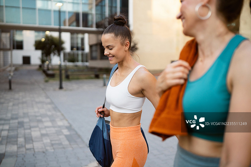 两位运动健将，在完成健身房的锻炼后，轻松愉快地走在回家的路上。图片素材