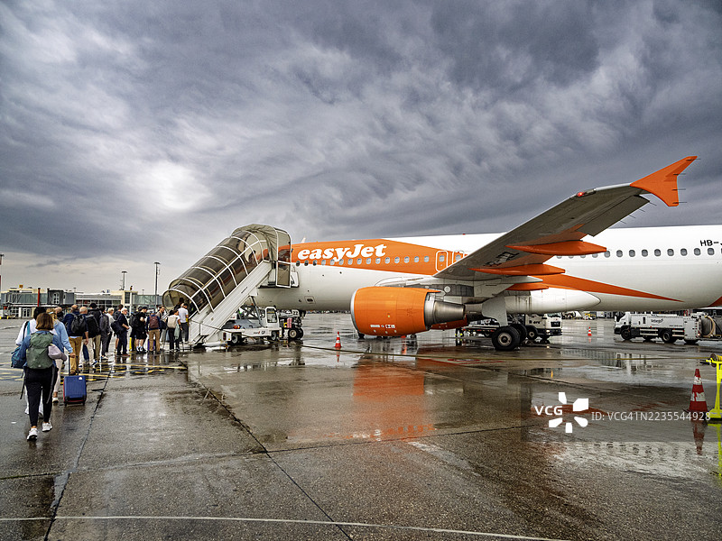 人们在瑞士日内瓦国际机场的跑道上登上EasyJet的空客A320飞机。图片素材