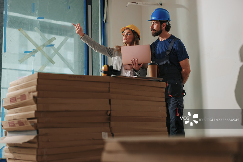 建筑师指着窗户与建筑工人讨论图片素材