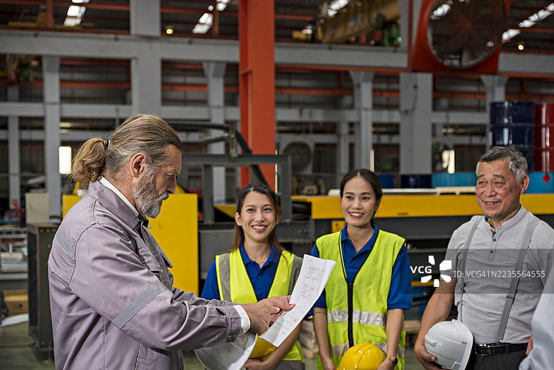 一位高级工厂经理在工作开始前向工人们进行工作简报。图片素材