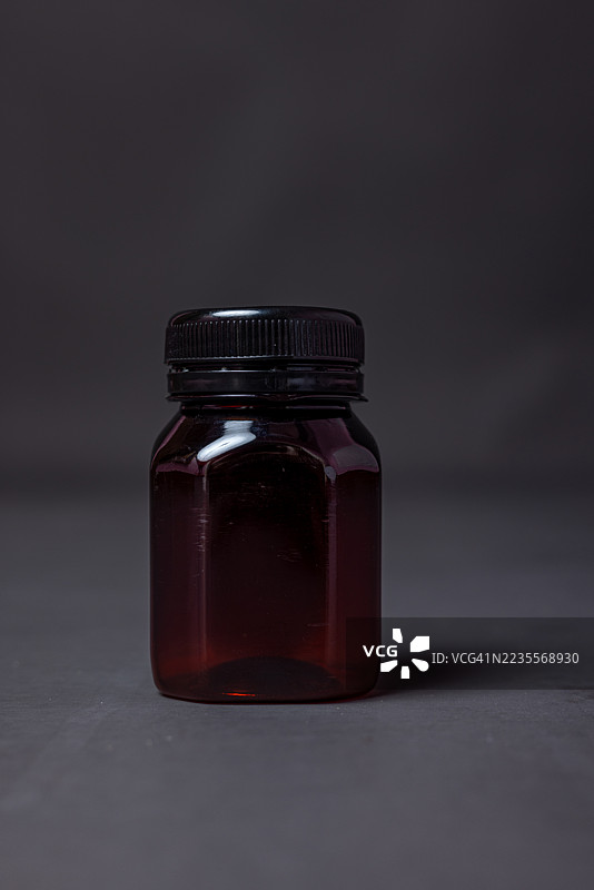 深琥珀色玻璃药瓶放在深色表面上图片素材