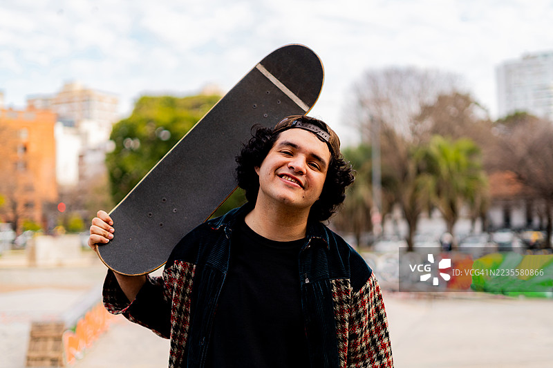 兴奋的年轻人在滑板公园里手持滑板的肖像图片素材