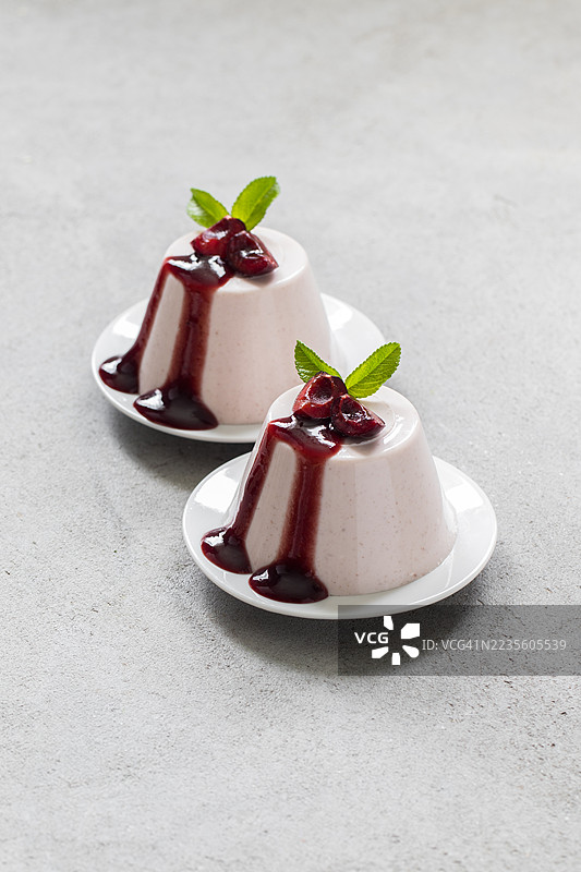 意大利甜点。樱桃奶油布丁，意式奶冻。配樱桃酱。放在盘子上。特写。图片素材