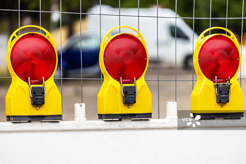 三盏红色警告灯和一个障碍物，背景中有汽车。图片素材