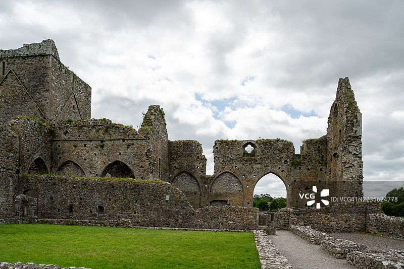 爱尔兰一座古老修道院的古代石头遗迹，在阴云密布的天空下，展示着建筑遗产和自然美景图片素材