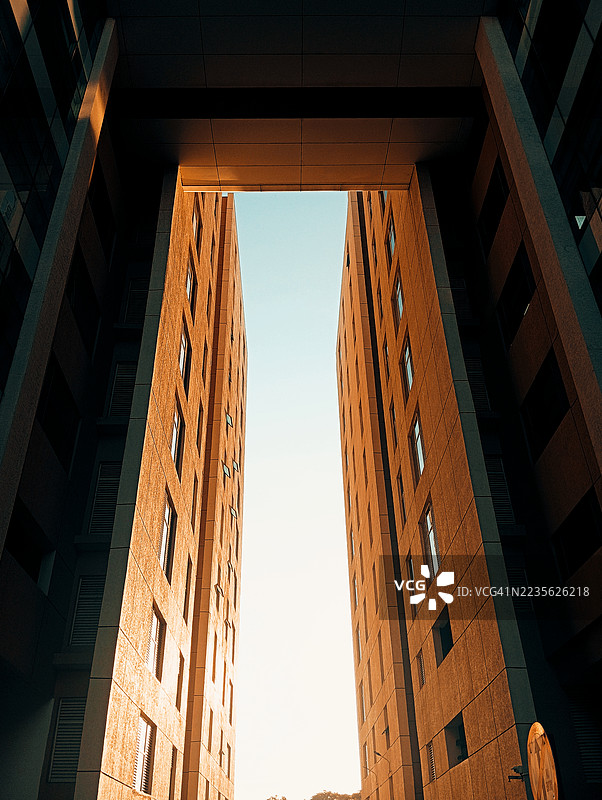 低角度视图下的现代建筑在晴朗的天空下，展示城市建筑和设计。图片素材