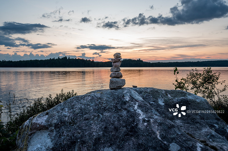 瑞典湖面上的宁静日落，岩石上的禅石堆图片素材