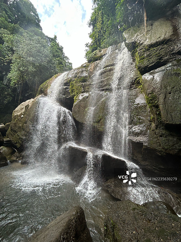 壮丽的瀑布倾泻而下，穿过郁郁葱葱的森林景观图片素材