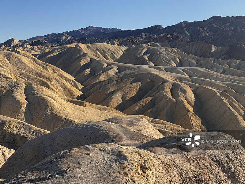 戏剧性的沙漠景观，起伏的丘陵在晴朗的蓝天下，唤起广阔和自然美的感觉，死亡谷，美国，USA图片素材