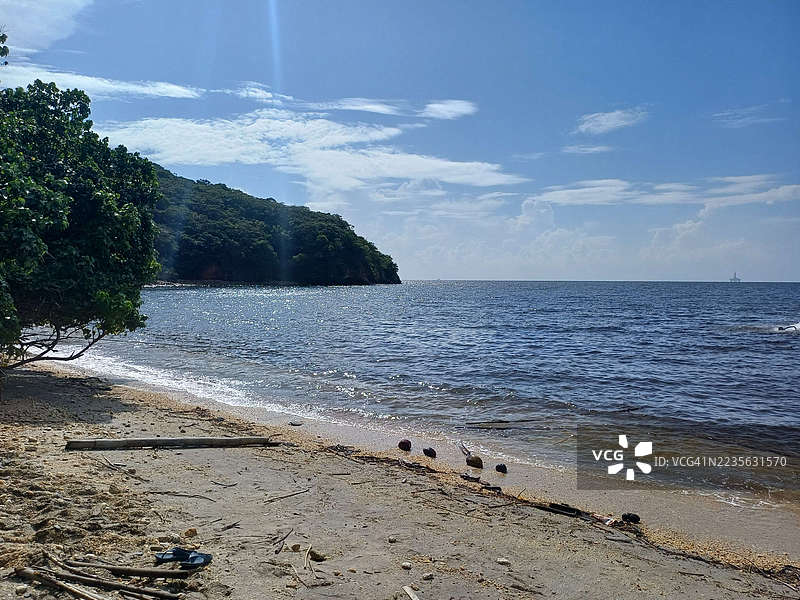 宁静的海岸风景，郁郁葱葱的绿色山丘和宁静的蓝色海洋在明亮的天空下，特立尼达和多巴哥，查卡查卡雷湾图片素材