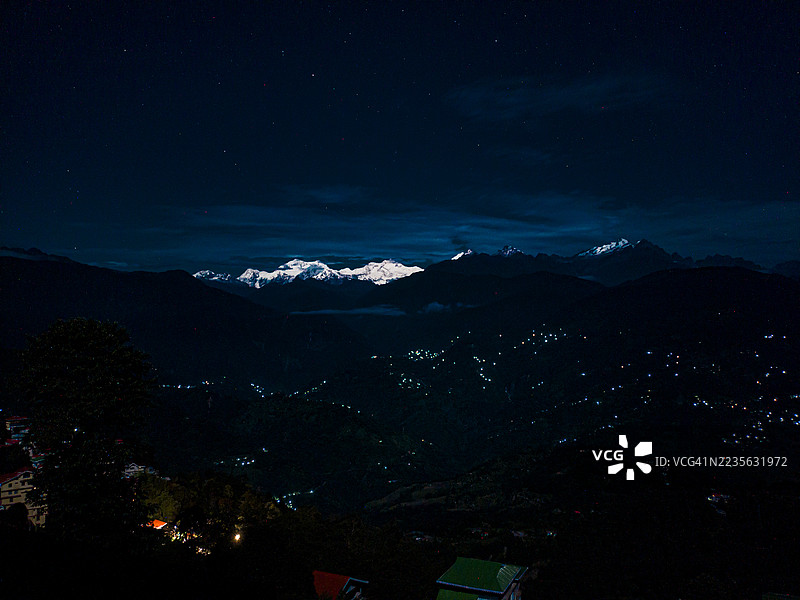 印度星空下雪山的迷人夜景，远处城市灯光闪烁。图片素材