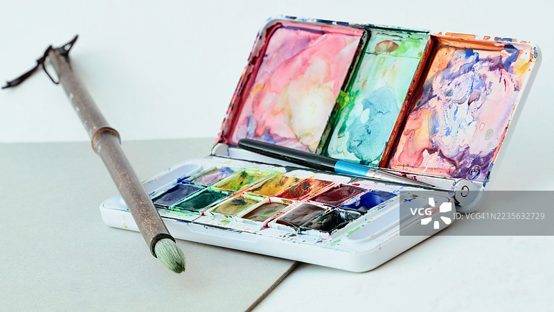 中性背景上水彩颜料套装和画笔的特写，突出创意和艺术表现力图片素材