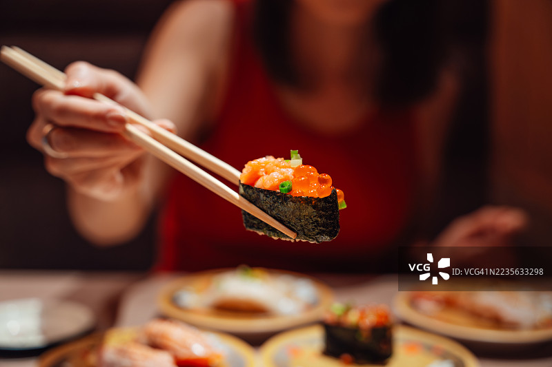 特写：一位女士在餐厅享用鲑鱼籽寿司（Ikura）图片素材