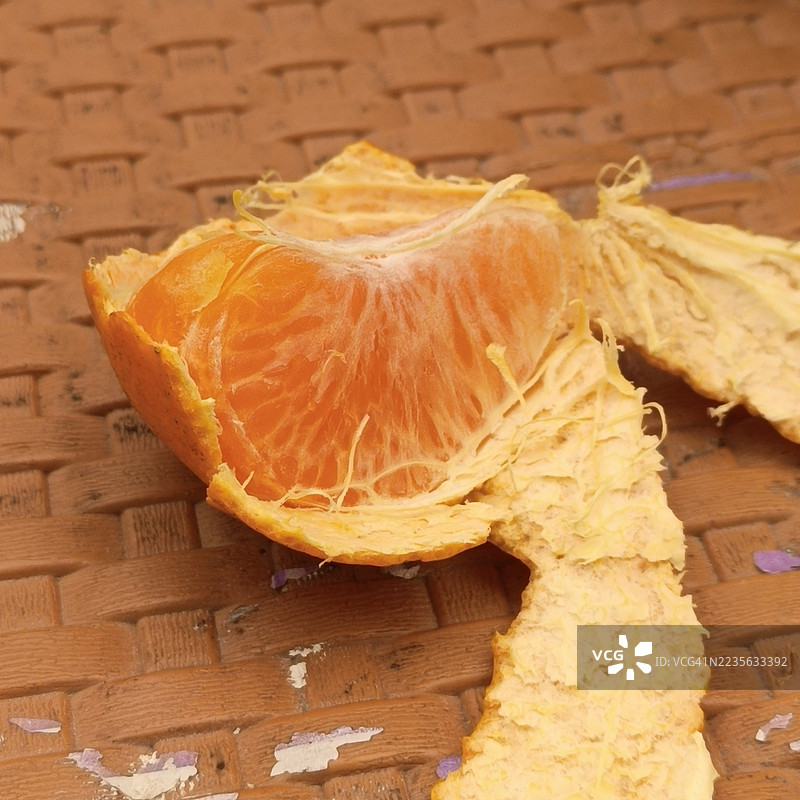 特写镜头展示了一只部分剥皮的鲜艳橙子，放在有纹理的表面上，突显其新鲜的果肉和果皮。图片素材