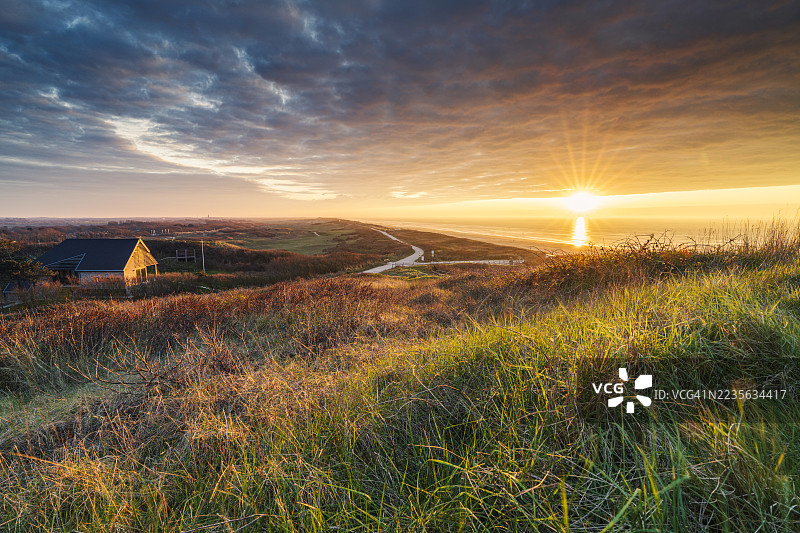 金色时光洒在海岸风景上，迷人的房子和通往阳光海洋的小径，位于荷兰多姆堡。图片素材