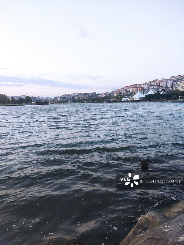 宁静的水面映照着天空，远处的城市天际线在柔和的光线下，土耳其图片素材