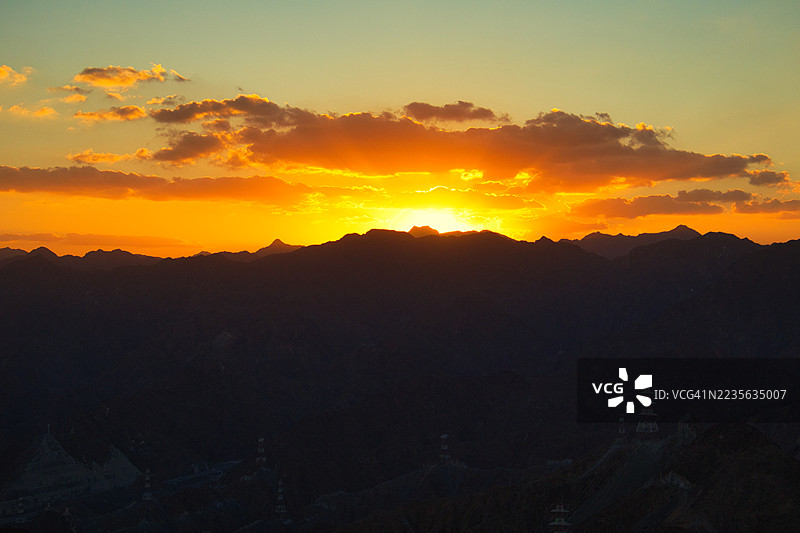 阿联酋富查伊拉，科尔法坎，山脉剪影上的戏剧性日落，天空色彩鲜艳，橙色和金色交织图片素材