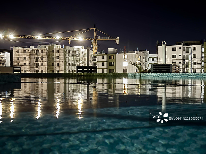夜晚游泳池中映照的灯光建筑和施工现场图片素材