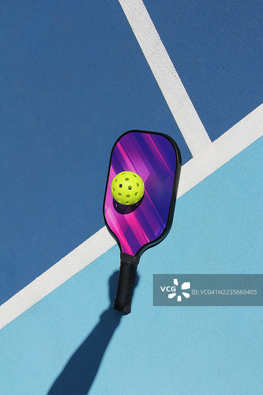 户外球场上，腌黄瓜球拍的正上方视角，手的阴影投射在拍子上图片素材