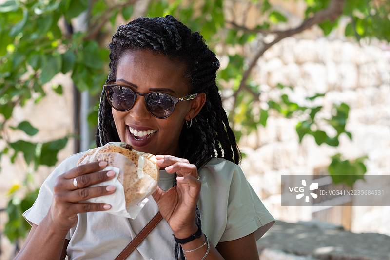 快乐的女士在户外享用沙拉三明治皮塔饼。图片素材