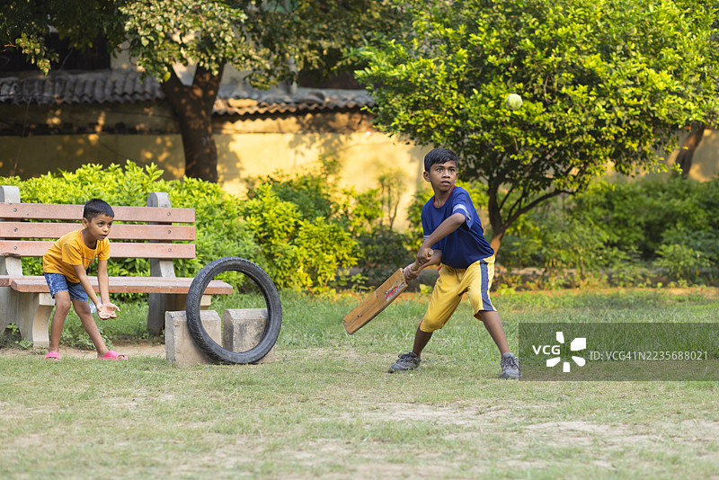 男孩在公园里打板球的肖像图片素材