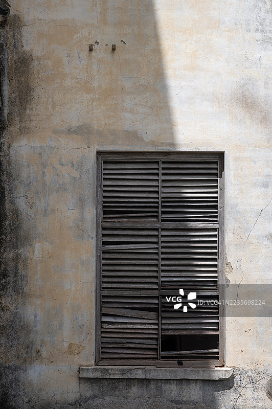 一扇嵌在风化墙壁上的旧木百叶窗。图片素材