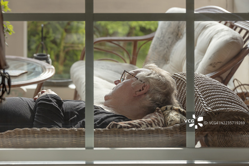 老年男子在露台沙发上睡觉，库存照片图片素材
