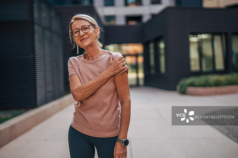 一位年长女性在户外锻炼后感到肩部疼痛图片素材