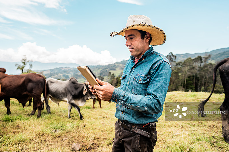 哥伦比亚昆迪纳马卡省一农场里，一位农民正在使用平板电脑的肖像照图片素材
