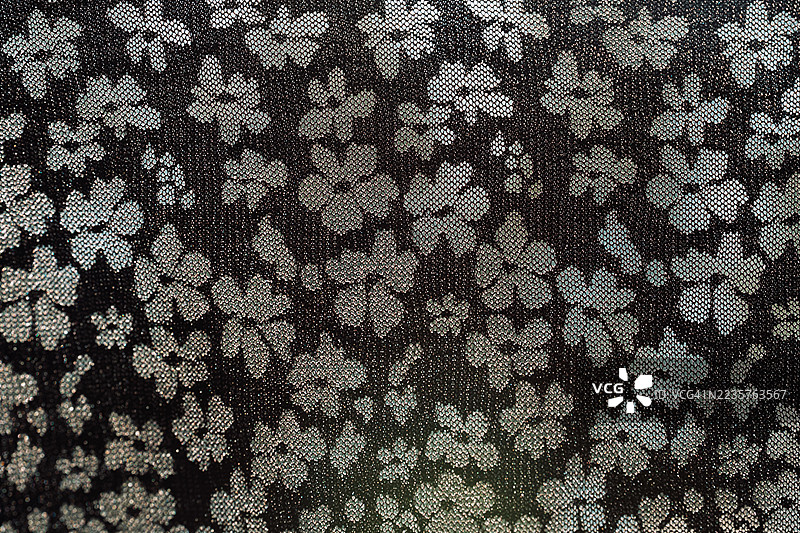 黑色蕾丝面料特写，带有花卉纹理，背景为粉色图片素材