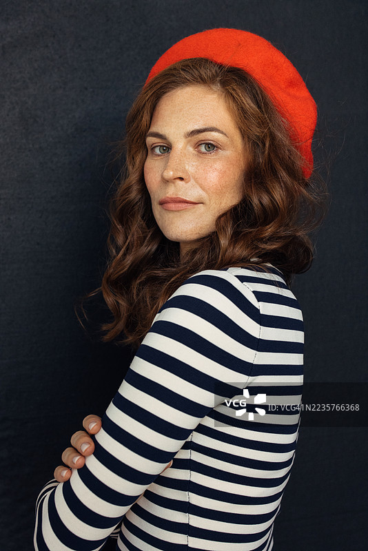 自信的女性穿着红色贝雷帽和条纹上衣的工作室肖像图片素材